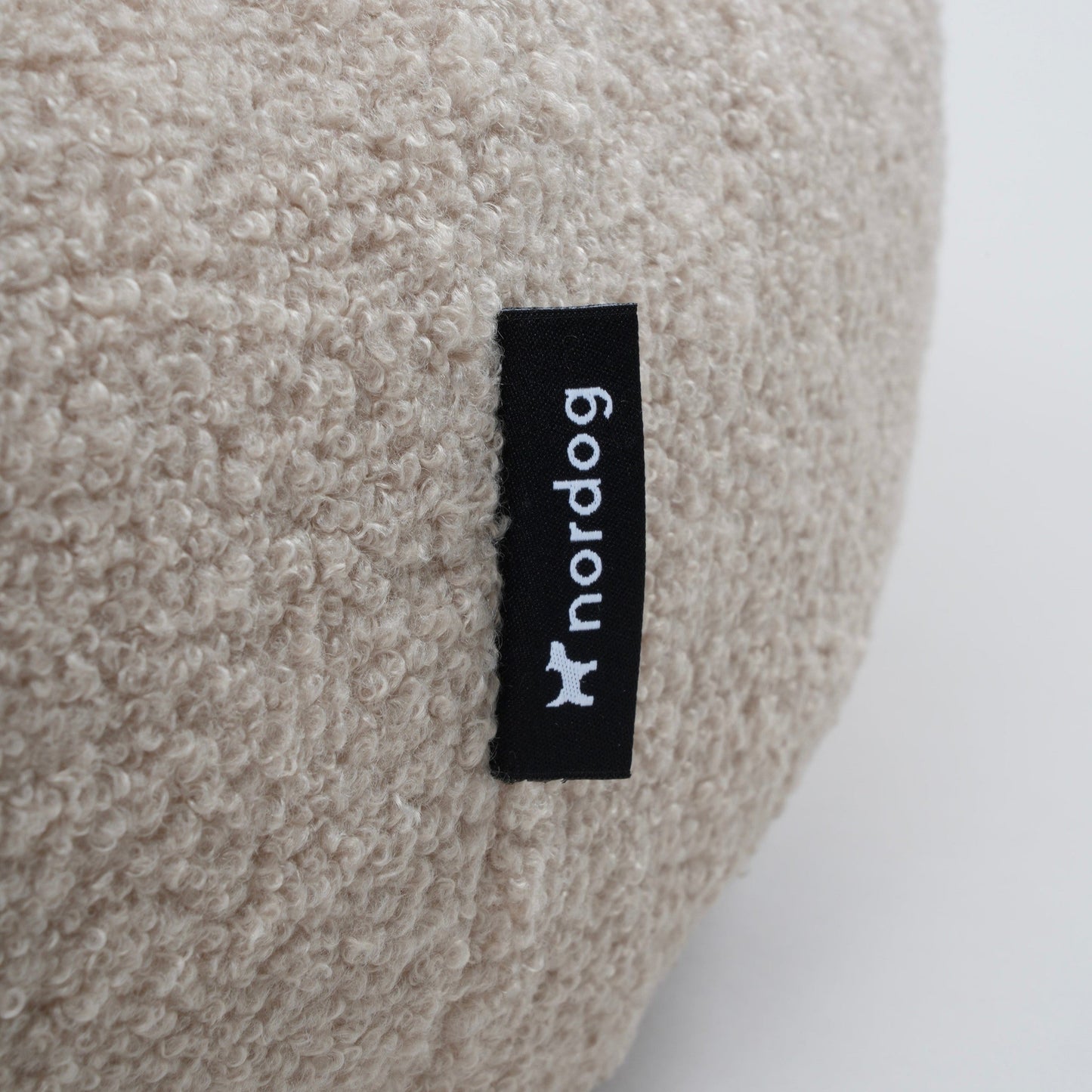 Beige cushion with a black label on a white background