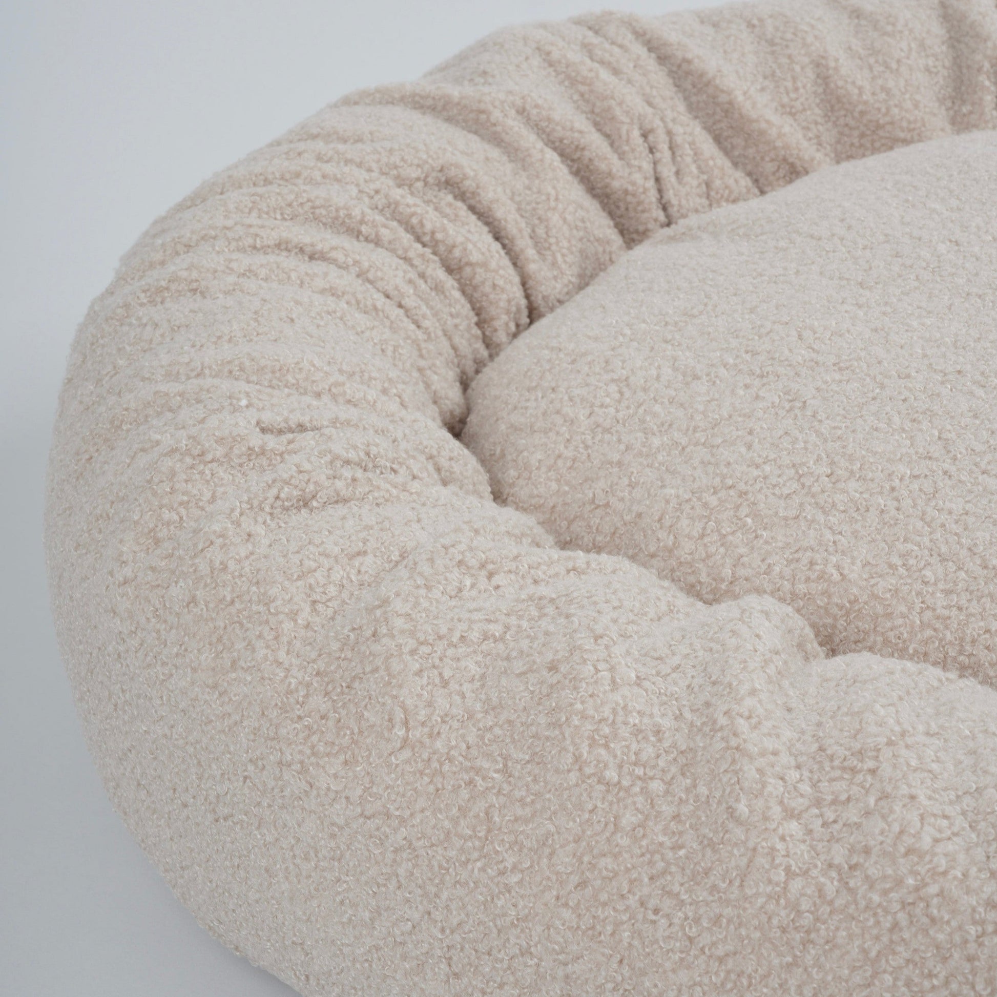 Beige pet bed with a soft texture on a light gray background