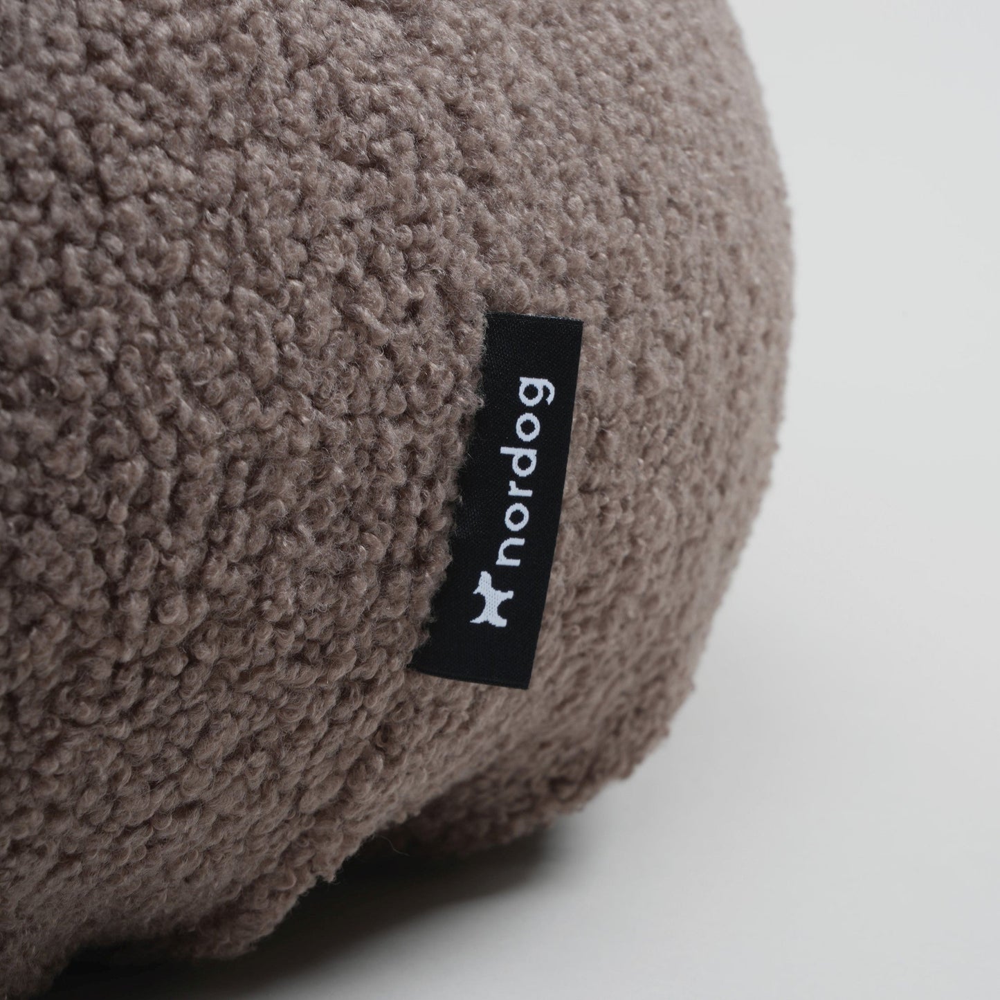 Brown textured pillow with a 'norddog' label on a white background