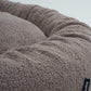 Close-up of a fluffy gray pet bed with a brand label on a light gray background